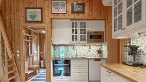Un interior de madera con una zona de cocina que incluye armarios, un microondas y un lavamanos.
