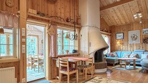 Un interior de madera con chimenea, mesa de comedor, sillas y sofá.