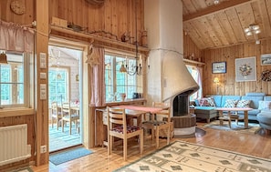 A wooden interior with a fireplace, dining table, chairs, and a sofa. - Lovely apartment in Sälen with sauna (Sälen)