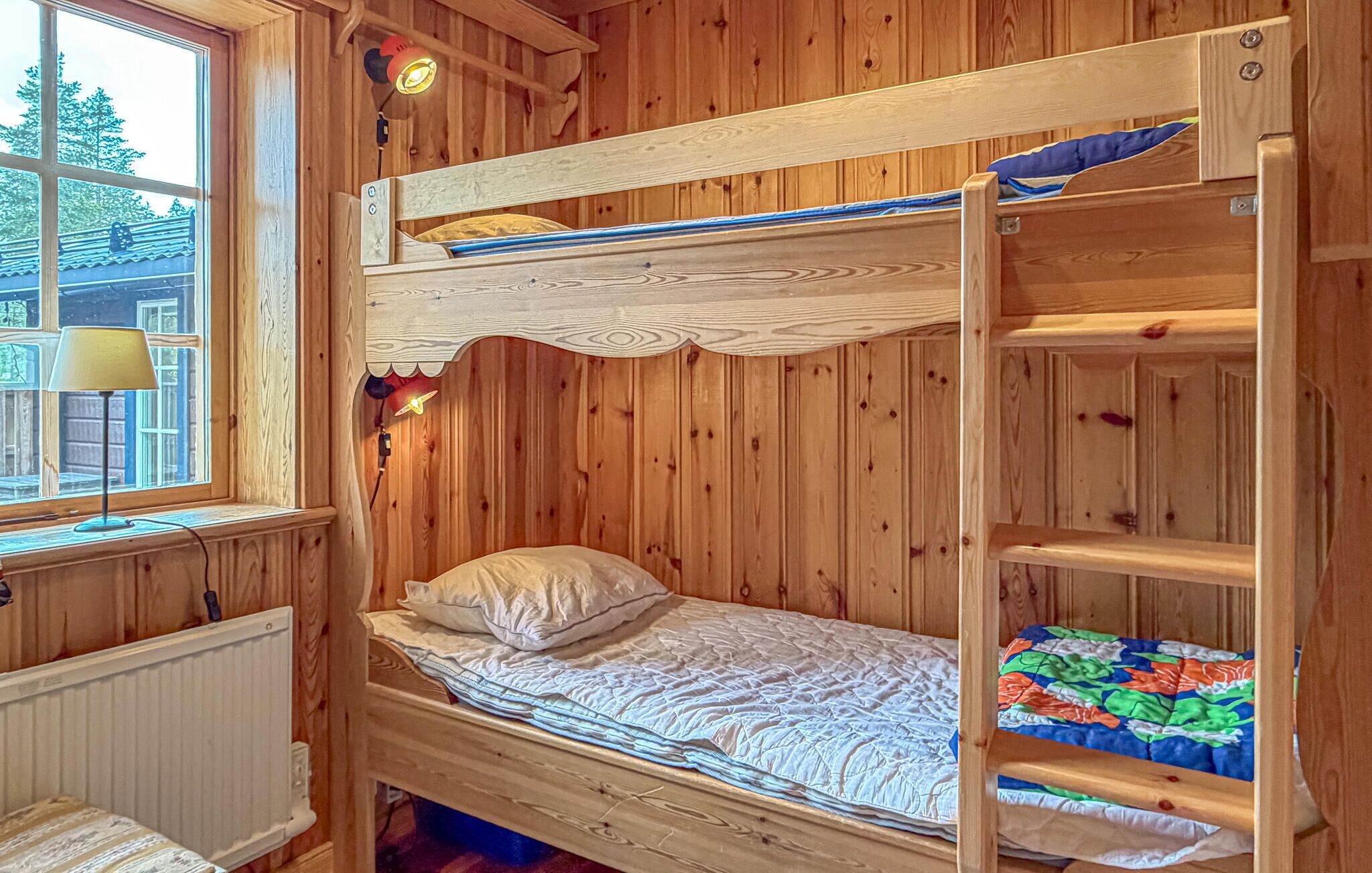 A bunk bed with a window, a lamp, and a radiator.