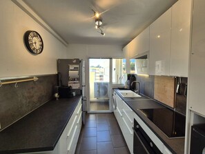 Une cuisine moderne équipée d’un four encastré, d’un évier et d’un ventilateur de plafond.
