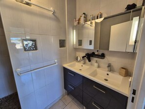 A modern bathroom with a walk-in shower, two sinks, a large mirror, and a towel rack. - 2 bedrooms, air-conditioned, WiFi, sea view, swimming pool (ST MANDRIER SUR MER)
