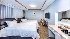 Ein Hotelzimmer mit zwei Betten, einem Schreibtisch, einem Stuhl, einem Fernseher und einem kleinen Tisch.