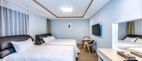 Quarto de hotel com duas camas, uma escrivaninha, uma cadeira, uma televisão e uma mesinha.