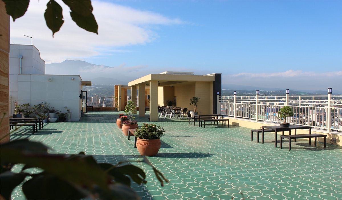 A rooftop terrace with outdoor seating, potted plants, and a view of the cityscape.