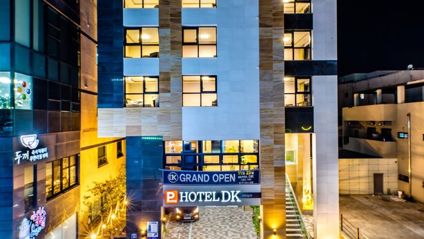 Ein Hotel Eingang mit einer großen, offenen Schautafel, einem Parkschild und einer sichtbaren Treppe, die zum Eingang führt.