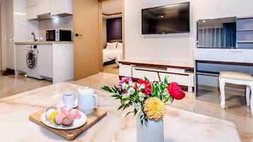 Quarto de hotel moderno com área de refeições, TV na parede, cama e uma pequena escrivaninha.