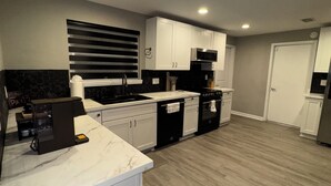 Une cuisine moderne avec des meubles blancs, un plan de travail noir et un plancher en bois.
