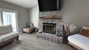Un salon moderne avec une cheminée en pierre, un téléviseur à écran plat et deux canapés.
