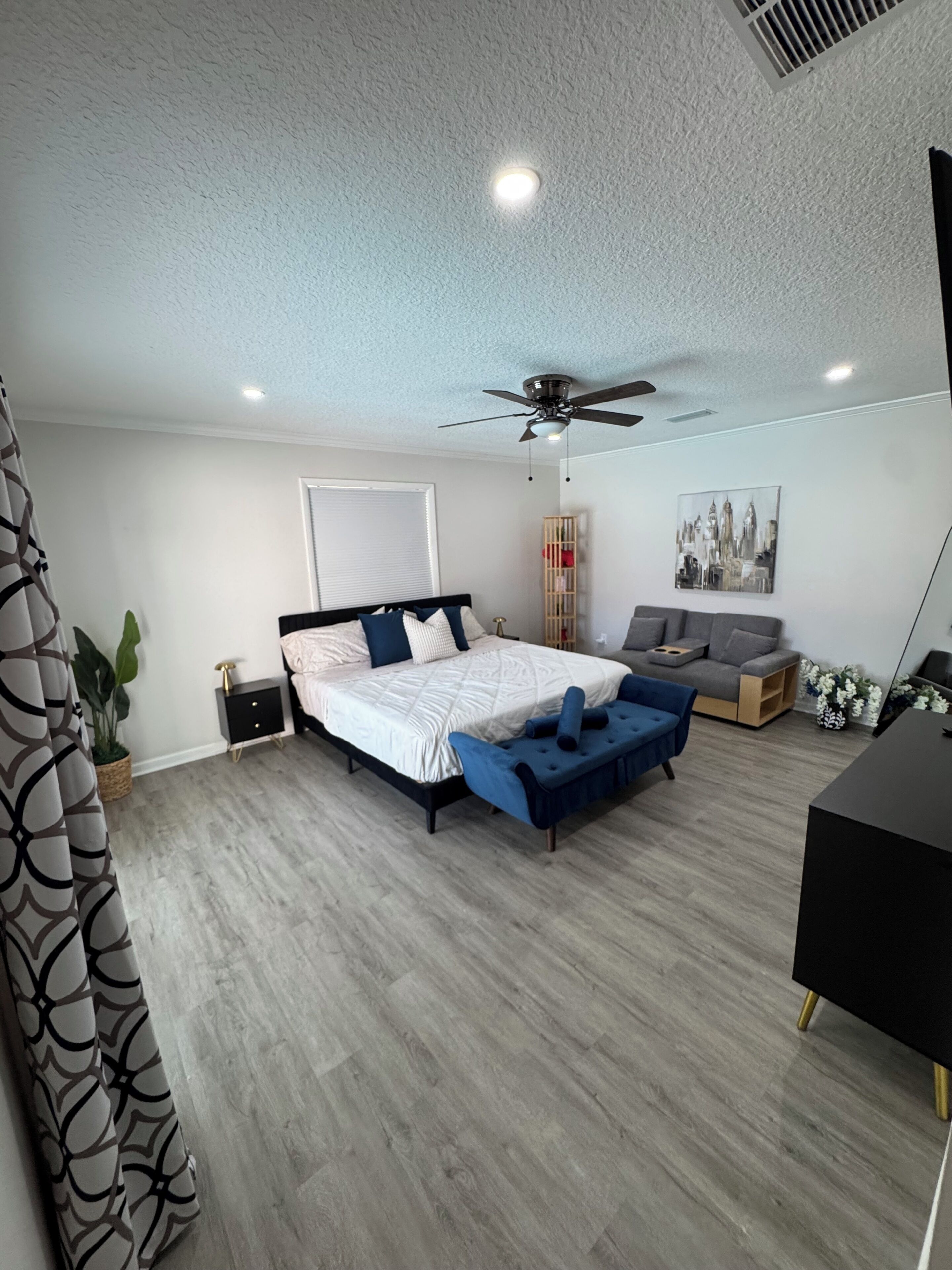 Una camera da letto moderna con un letto, una panca blu, una scrivania e una ventola a soffitto.