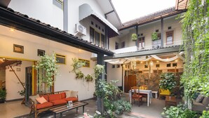 Un patio con sofá, mesa, sillas y plantas en macetas.
