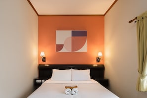 Hotellihuone, jossa on sänky, kaksi yöpöytävalaisinta, seinätaideteos ja ikkuna, jossa on verhot.