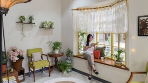 Un rincón acogedor para leer, con ventana, una silla, una mesita y una estantería.