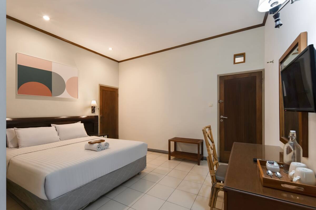 Ein Hotelzimmer mit Bett, Nachttisch, Fernseher und einer kleinen Sitzecke.