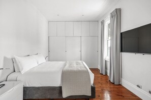 A modern bedroom with a bed, a wardrobe, and a television. - Launceston Townhouse Hospital, CBD & Cafes (Launceston)