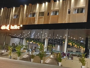 A hotel with a modern facade, large windows, and outdoor seating area with potted plants.