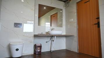 A bathroom with a marble wall, a wooden door, a white sink, and a toilet.