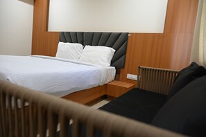 Quarto de hotel com cama, mesa de cabeceira e uma cadeira.