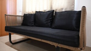 Een zwarte bank met houten frame en een metalen radiator links ervan.