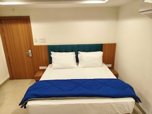 Un lit simple avec une tĂȘte de lit turquoise, du linge de lit blanc et une couverture bleue.