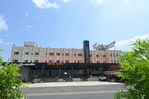 Un hotel de varios pisos con fachada plana, una entrada destacada y un letrero que indica que es un hotel.