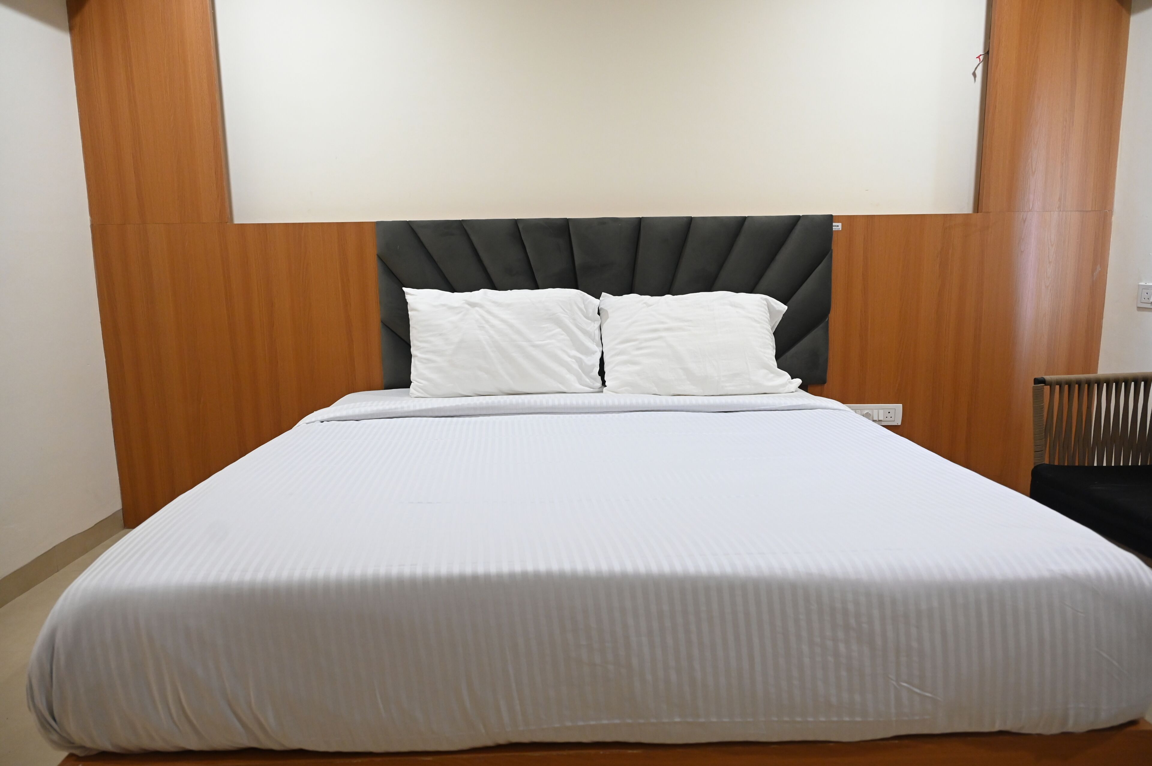 A single bed with a headboard, white bedding, and a wooden wall paneling.