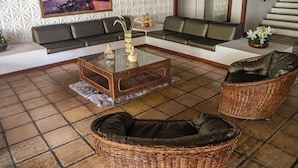 A modern living room with a sofa set, a coffee table, and wicker chairs. - Ed. Studio Oceânico (Salvador)