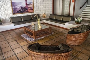 Un salon moderne avec un ensemble de canapés, une table basse et des fauteuils en osier.