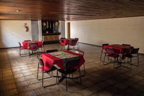 A room with multiple tables and chairs, a wooden ceiling, and a fire extinguisher on the wall. - Ed. Studio Oceânico (Salvador)