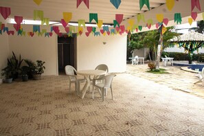 Un patio coperto con pavimento piastrellato, un tavolo rotondo con sedie e vivaci bandierine di carta.