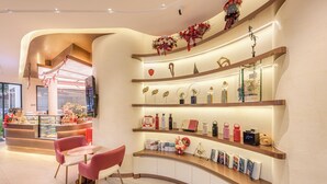 A hotel reception area with a curved counter, red chairs, and a display of amenities including water bottles, a clock, and decorative items. - Thadatra Inn (Phnom Penh)