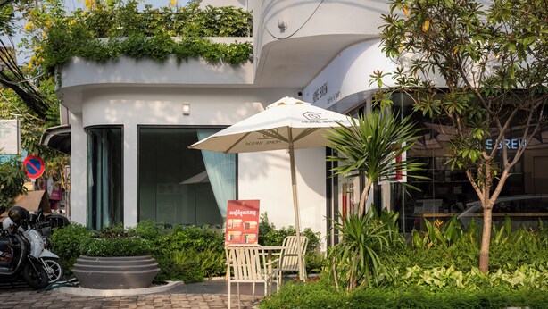 An outdoor seating area with a table and chairs, a signboard, and a motorcycle parked nearby. - Thadatra Inn (Phnom Penh)