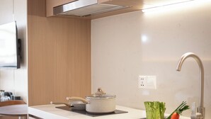 A modern kitchen with a stainless steel sink, a stove, and a countertop with a pot and vegetables. - Thadatra Inn (Phnom Penh)