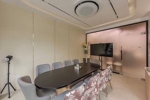 A conference room with a long table, chairs, a tripod, and a television on the wall. - Thadatra Inn (Phnom Penh)