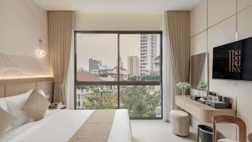 Habitación de hotel con una cama grande, un escritorio, un televisor y vistas a la ciudad.