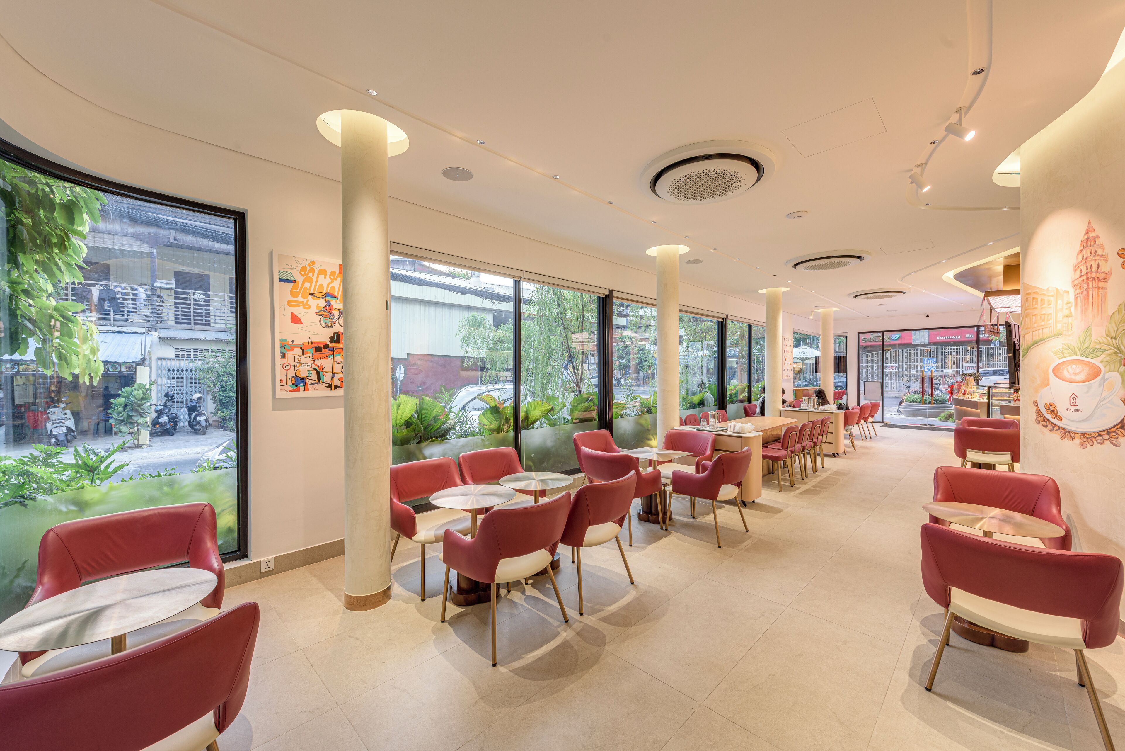 Un interior de cafetería moderno con sillas rojas, mesas redondas, ventanas amplias y vistas a la calle.