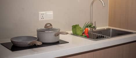 A kitchen with a modern design, featuring a stainless steel sink, a kettle, and a bowl on a black mat.