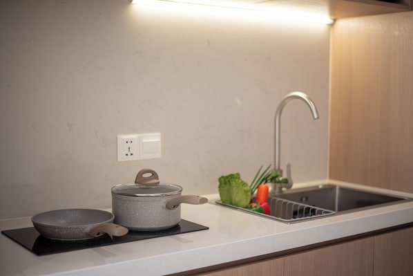 A kitchen with a modern design, featuring a stainless steel sink, a kettle, and a bowl on a black mat. - Thadatra Inn (Phnom Penh)