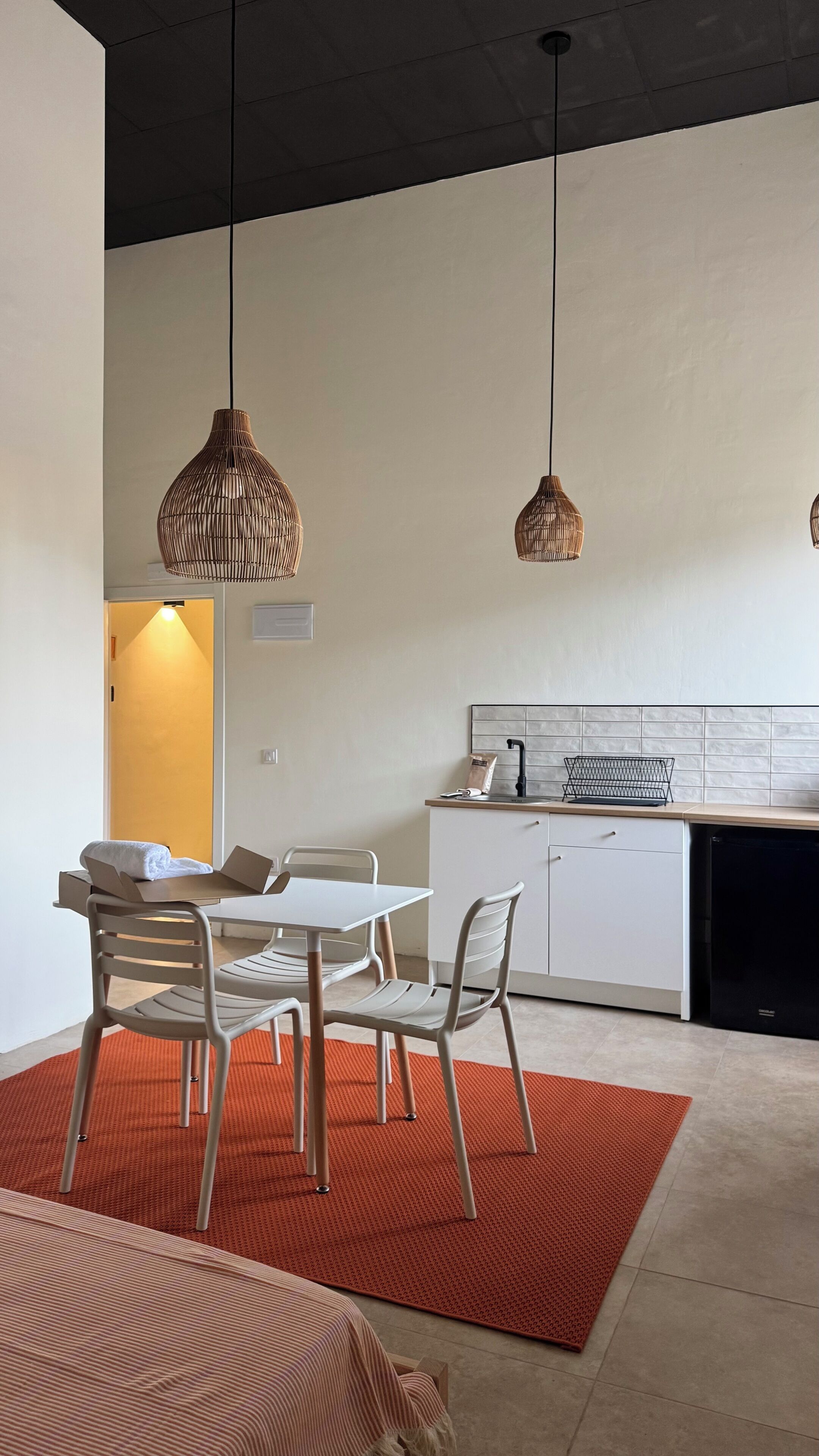 Une cuisine moderne avec des meubles blancs, un lave-vaisselle noir et un tapis rouge.