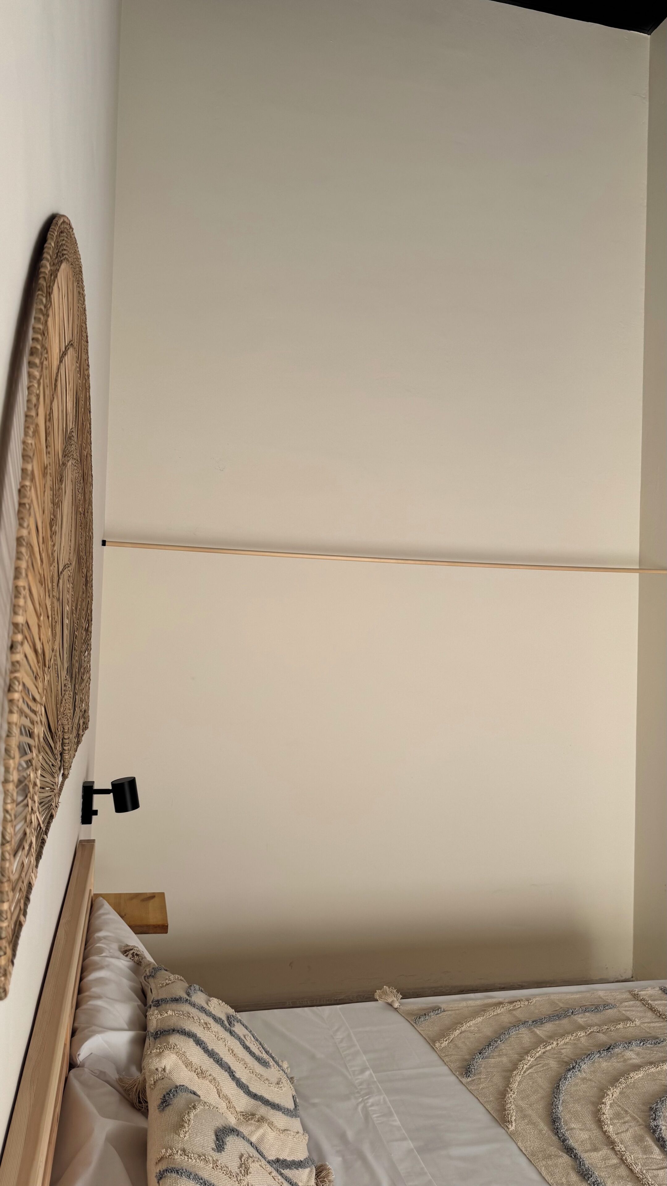 Una cama con cabecera de madera, una lámpara de noche y una manta decorada.