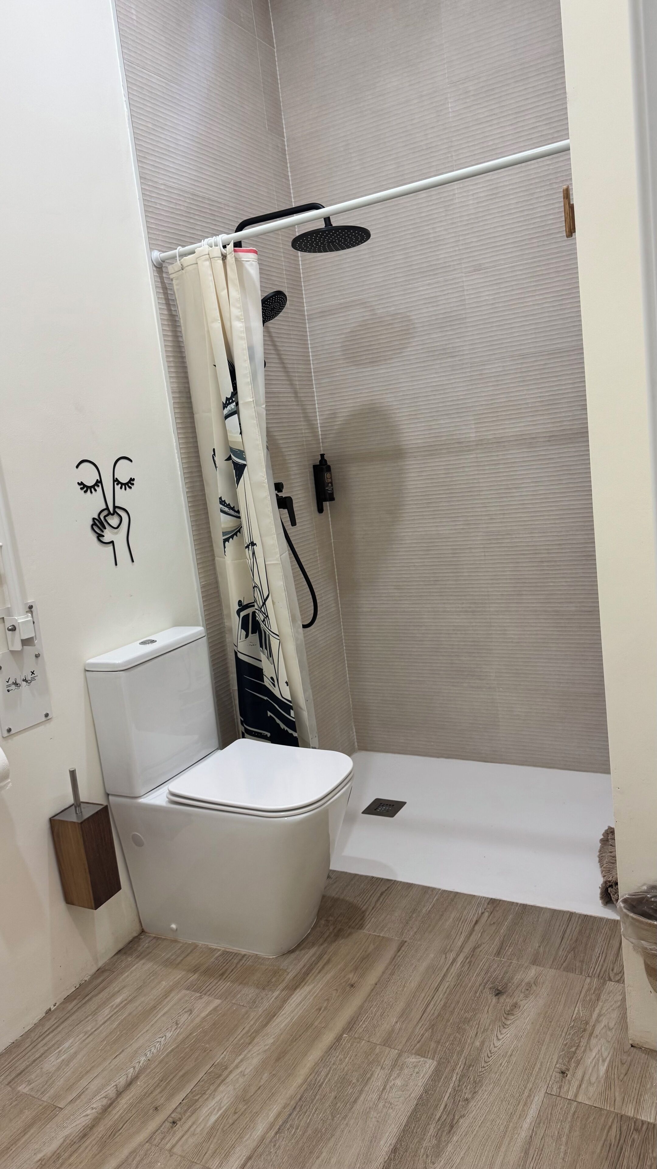 A bathroom with a toilet, shower, and a wall-mounted toilet paper holder.