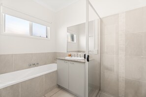 Une salle de bain moderne avec une baignoire, une douche à parois de verre et un meuble-lavabo avec un miroir.