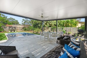 A covered patio with a pool, outdoor furniture, and a view of the backyard. - Coastal 4-bed Retreat With Pool in Toogoom (Toogoom)