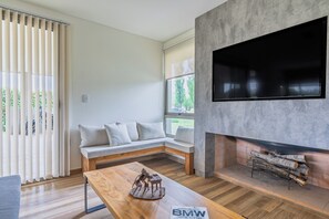 A modern living room with a sofa, a wooden coffee table, a fireplace, and a TV mounted on a concrete wall. - MOT Tupungato Entrevides (Tupungato)