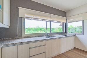 A kitchen with a window, a sink, and wooden cabinets. - MOT Tupungato Entrevides (Tupungato)