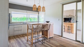 Una cocina moderna con un amplio ventanal, un comedor con sillas de mimbre y una chimenea de piedra.