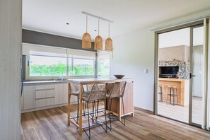 Una cucina moderna con un'ampia finestra, un'area pranzo con sedie in vimini e un camino in pietra.