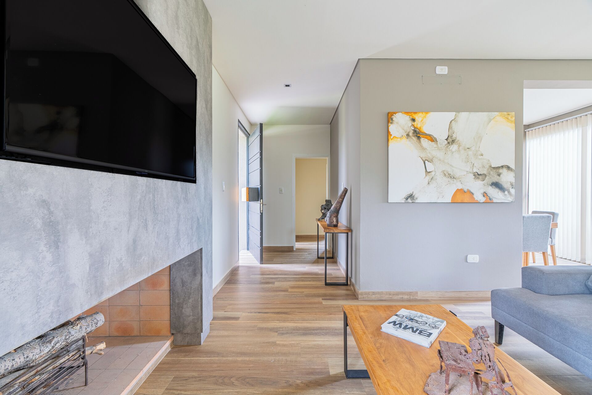 A modern living room with a fireplace, a large abstract painting, and a sofa.