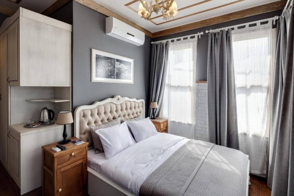 Una camera da letto con un letto, comodini, un armadio, un quadro incorniciato e una finestra con tende.