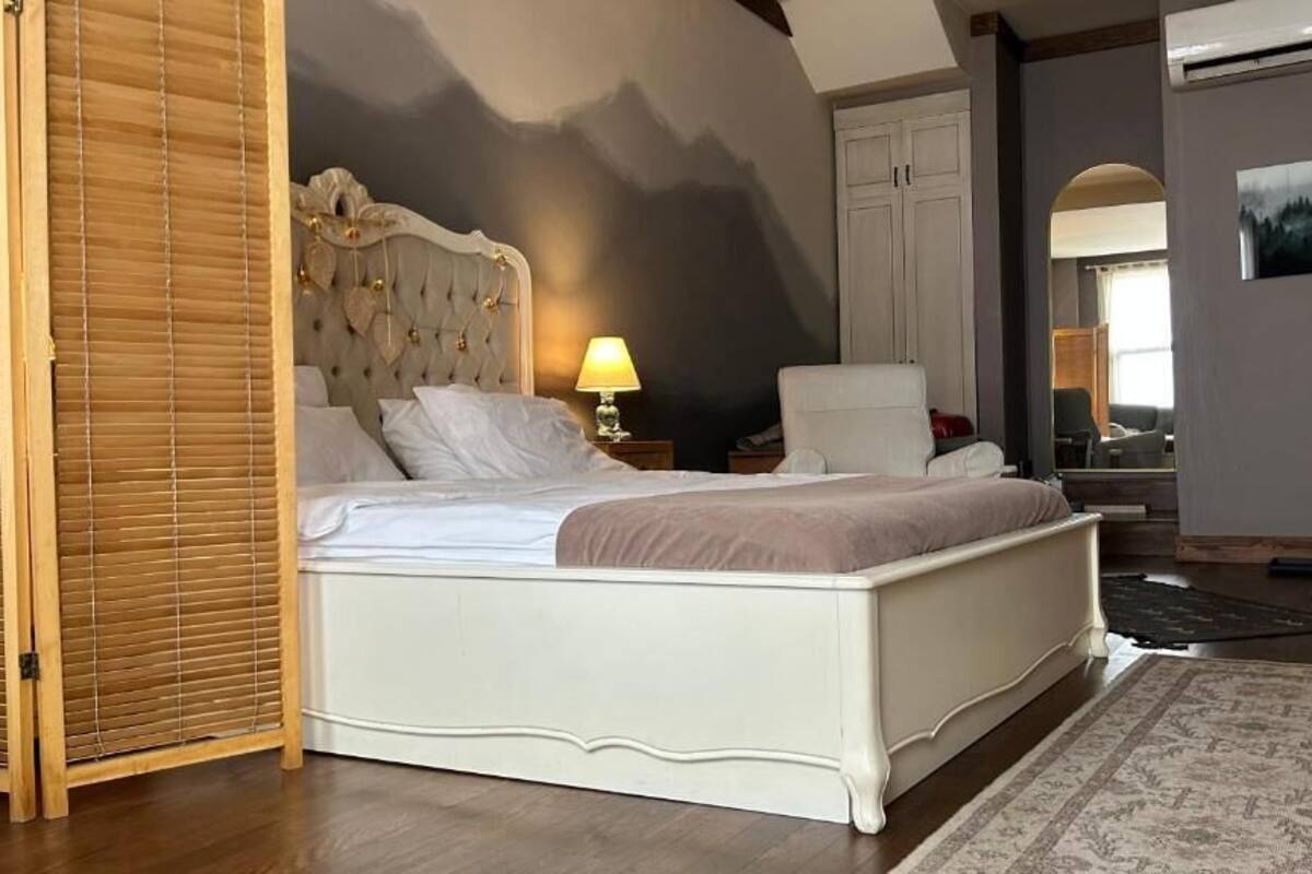 Una camera da letto con un letto, una sedia, una lampada, un armadio e un quadro appeso al muro.